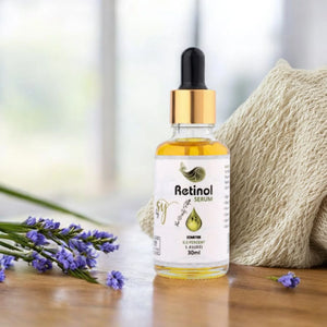 Retinol serum bottle with gold dropper, purple flowers, and textured towel on wooden surface