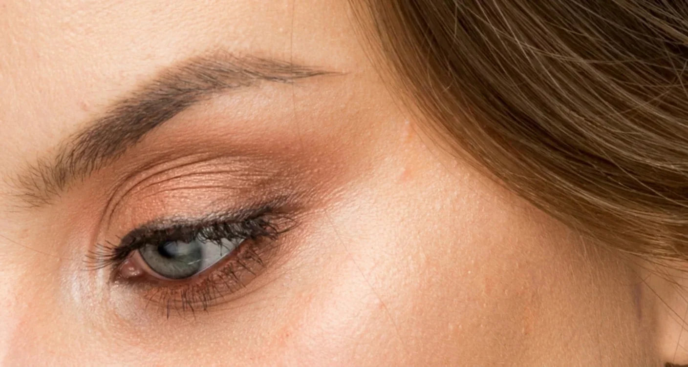 Close-up of a woman's eye with natural brown eyeshadow and groomed eyebrow
